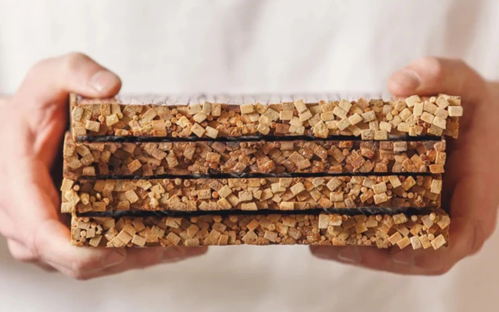 Hands holding a stack of ChopValue tiles made from pressed recycled chopsticks