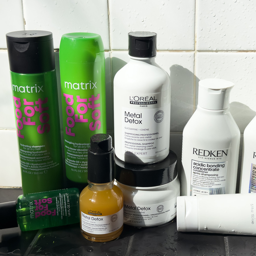 Collection of hair care products including Matrix and L'Oreal on a tiled bathroom shelf.